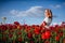 Cheerful girl with curly blond hair in a huge poppy field alone,