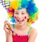 Cheerful girl in curly clown wig and party horn blower