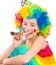 Cheerful girl in curly clown wig and party horn blower