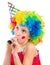 Cheerful girl in curly clown wig and party horn blower