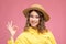 Cheerful girl with curly hair with a beautiful bright make-up in a yellow dress and a straw hat
