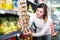 Cheerful girl customer looking for tasty snacks in supermarket