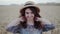 Cheerful girl in dress and hat walks in wheat field and smiles at camera