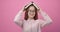 Cheerful girl in eyeglasses holding opened book on head