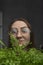 Cheerful girl with glasses holds green houseplant. Close-up portrait of young woman with Houseplant. Vertical frame