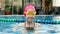 Cheerful girl in goggles bathing in the pool. Cute child little girl in the pool in swimming goggles splashes water in