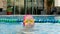 Cheerful girl in goggles bathing in the pool. Cute child little girl in the pool in swimming goggles splashes water in