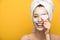 Cheerful girl with nourishing facial mask covering eyes with heart-shaped cosmetic sponge