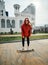 Cheerful girl in the orange hoodie rides on street on a longboard