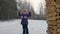 Cheerful girl peeping out from trees in winter forest playing hide and seek