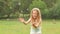 Cheerful girl plays catch soap bubbles on the meadow. Slow motion. Close up