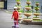 A cheerful girl is standing on a roller skating ride in a city park. A small child in a pink jacket and helmet is on rollers