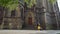 Cheerful girl in sweater and yellow skirt runs down steps of church and begins to spin in sun