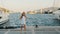 Cheerful girl teenager dancing on quay on sea port and yacht background. Happy girl having fun on embankment, ships and