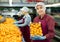 Cheerful girl worker with box of tangerines at fruit sorting factory