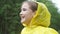 Cheerful girl in yellow raincoat laughs looking around