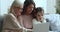 Cheerful girls and women of three family generations using laptop