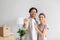 Cheerful glad millennial man in glasses and female showing keys in empty room with cardboard boxes