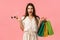 Cheerful gorgeous caucasian woman in dress, holding shopping bags and sunglasses, smiling intrigued and excited, seeing