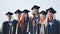 Cheerful graduates pose with raised diplomas on a sunny day.