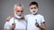 Cheerful granddad and grandson in shaving foam showing razors, mans rituals