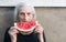 Cheerful grandma eating watermelon in the backyard