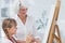 Cheerful grandmother and granddaughter painting together