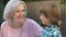 Cheerful grandmother talking to little boy and smiling at camera, happy family