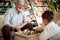 A cheerful Grandpa enjoys playing the chess at home with his little grandson. Family, game, together