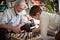 A cheerful Grandpa and his little grandson enjoy playing the chess at home. Family, game, together