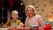 Cheerful granny and girl smiling, satisfied with Christmas cooking, holidays