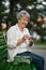 Cheerful granny opens a gift box on the bench