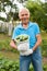 Cheerful gray-haired man with harvest of cucumbers on his farm