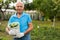 cheerful gray-haired man with harvest of cucumbers on his farm