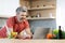 Cheerful grey-haired man cooking at home, reading food blog