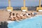 Cheerful group of eight beautiful female friends in the swimming pool  with inflatable mattress. The blue ocean in background.