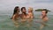 Cheerful group of people having fun swimming in sea action camera pov of young playful friends together on beach