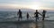 Cheerful Group Of People Running From Sea Holding Hands, Happy Friends Together On Beach At Sunset