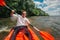 Cheerful guy sits in red kayak and row with a paddle