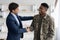 Cheerful guy in suit shaking black military man hand