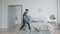 Cheerful guy vacuuming carpet at home and dancing with vacuum cleaner