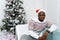 Cheerful handsome African American male looking at camera and smiling indoor near Christmas glowing decorated tree