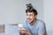 Cheerful handsome man with cute raccoon on head holding coffee cup while sitting on bedding.