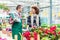 Cheerful handsome worker in a flower shop talking with a beautiful customer