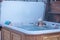 Cheerful happy company of teenagers enjoys hot bath in jacuzzi whirlpool on cold winter day. Carefree relaxation in hot