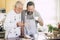 Cheerful and happy couple father son middle age and senior mature cooking cake together at home at the kitchen. using sugar and