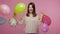 Cheerful happy energetic brunette woman laughing and dancing with colorful air balloons, enjoying birthday party