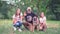 A Cheerful And Happy Family With A Big Dog Are Sitting On The Grass And Smiling