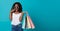 Cheerful happy teen african woman enjoying shopping, she is carrying shopping bags to get the latest offers at the shopping center