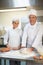 Cheerful head chef showing trainee how to prepare dough